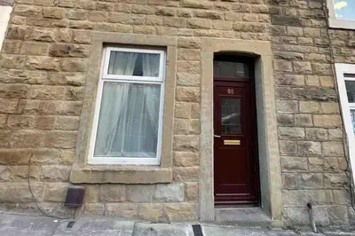 a brick building with a red door and a window at Accrington Three Bed in Accrington