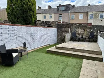 a patio with chairs and a brick wall and grass at Accrington Three Bed in Accrington