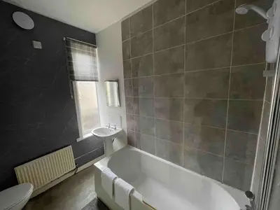 a bathroom with a bath tub and a sink at Accrington Three Bed in Accrington