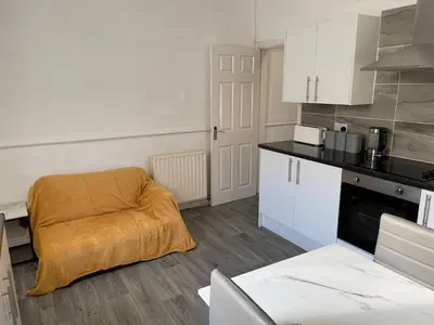 a kitchen with a orange blanket on a chair at Accrington Three Bed in Accrington