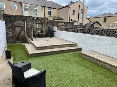 a backyard with chairs and a patio with grass at Accrington Three Bed in Accrington