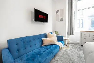 a blue couch in a living room with a tv at Aurum House Luxury Apartments in Blackpool