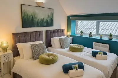 two beds with pillows on them in a bedroom at Belgrave Chapel - Luxurious Apartment in Darwen