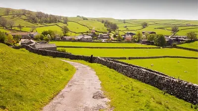 a dirt road in a field next to a stone wall at Belgrave Chapel - Luxurious Apartment in Darwen