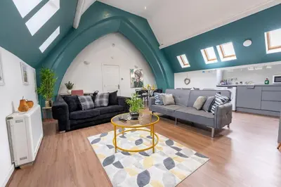 a living room with two couches and a table at Belgrave Chapel - Luxurious Apartment in Darwen