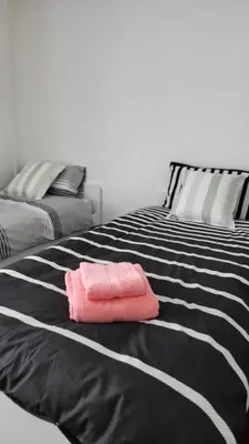 a black and white bed with a pink towel on it at House4 holiday in Liverpool
