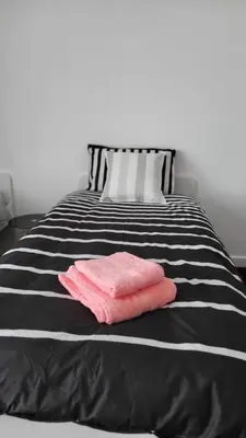 a black and white bed with two pink towels on it at House4 holiday in Liverpool