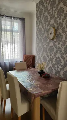 a dining room table with a laptop and a clock on the wall at House4 holiday in Liverpool