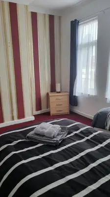 a bedroom with a bed with a blanket and a window at House4 holiday in Liverpool
