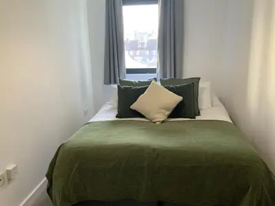 a bed with green and white pillows and a window at Spacious City Centre 2 Bedroom Apartment in Liverpool
