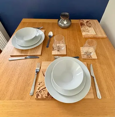 a wooden table with two white plates and glasses on it at Garrick's Suite-Home away from Home- suitable for couples retreat, Contractors and NHS- free parking in Southport