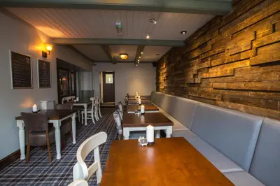 a restaurant with wooden walls and tables and chairs at The Sun Inn in Ulverston