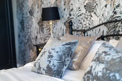 a bedroom with a bed with pillows and a wall at The Sun Inn in Ulverston