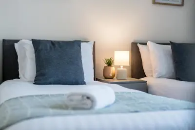 a bedroom with two beds and a table with a lamp at Randolph House - Air Host & Stay - Sleeps 6 in Liverpool