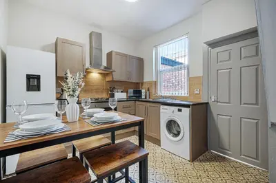 a kitchen with a dining table and a laundry machine at Randolph House - Air Host & Stay - Sleeps 6 in Liverpool