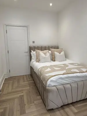 a bedroom with a large bed with white walls and wooden floors at Seaside Retreat Luxury Apartment in Liverpool
