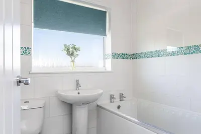 a white bathroom with a sink and a toilet and a window at Curlew Stays - Semi Detached Home - Pet Friendly in Thornton