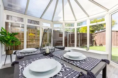 a glass conservatory with a table with plates on it at Curlew Stays - Semi Detached Home - Pet Friendly in Thornton