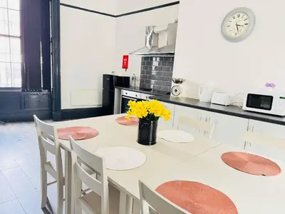 a kitchen with a table with chairs and a clock at Pembroke Place Private Room 9 in Liverpool