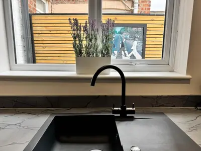 a kitchen sink with a vase of flowers in a window at Garden, Free Parking, Smart TV, Self Check in in Liverpool