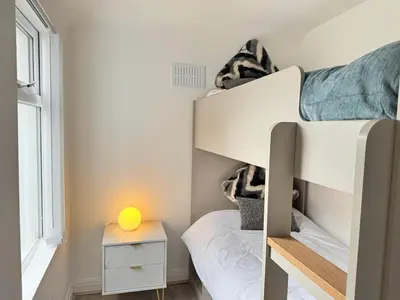 a small bedroom with a bunk bed with a yellow lamp at Garden, Free Parking, Smart TV, Self Check in in Liverpool