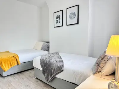 two beds in a room with white walls and a lamp at Garden, Free Parking, Smart TV, Self Check in in Liverpool