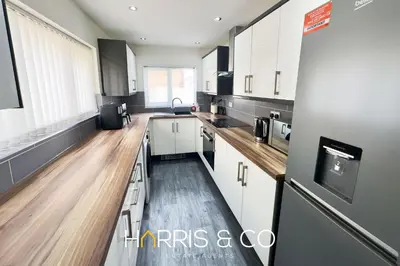 a large kitchen with white cabinets and wooden floors at Bosun's Bay in Fleetwood