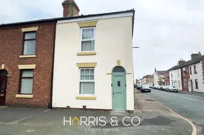 a white house with a green door on a street at Bosun's Bay in Fleetwood