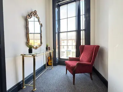 a living room with a chair and a mirror at Pembroke Place Private Room 1 in Liverpool