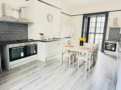 a white kitchen with a table and chairs in it at Pembroke Place Private Room 1 in Liverpool