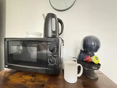 a microwave sitting on top of a wooden table with cups at Pembroke Place Private Room 1 in Liverpool