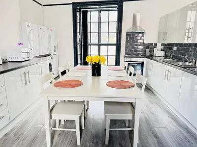 a white kitchen with a white table and chairs at Pembroke Place Private Room 6 in Liverpool