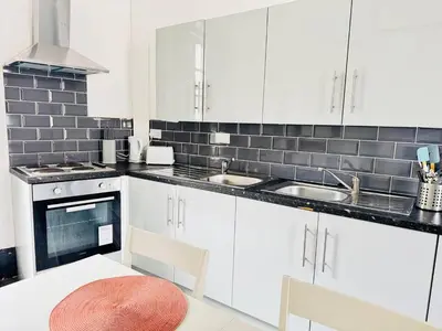 a kitchen with white cabinets and a white table and chairs at Pembroke Place Private Room 7 in Liverpool