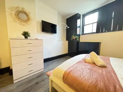 a bedroom with a bed and a dresser and a television at Pembroke Place Private Room 11 in Liverpool