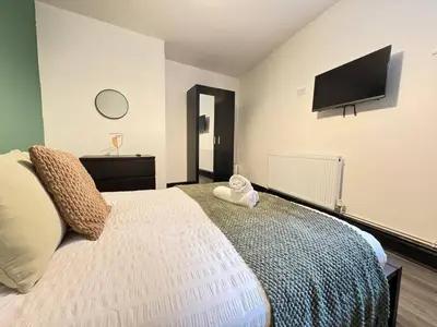 a bedroom with a bed with a television on the wall at Pembroke Place Private Room 10 in Liverpool