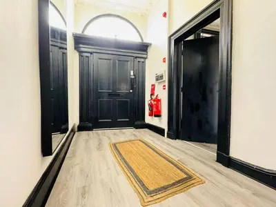 a hallway with black doors and a rug on the floor at Pembroke Place Private Room 10 in Liverpool