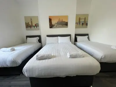 two twin beds in a room with paintings on the wall at The LFC Red House - Spacious House With 5 Bedrooms, 2 Bathrooms, Street Parking And 1 Minute From The Stadium in Liverpool