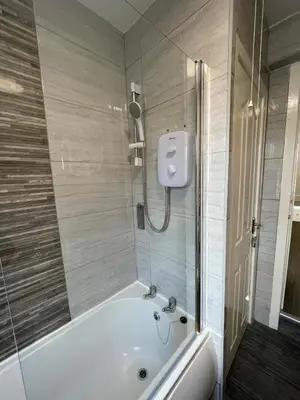 a bathroom with a white tub and a shower at The LFC Red House - Spacious House With 5 Bedrooms, 2 Bathrooms, Street Parking And 1 Minute From The Stadium in Liverpool