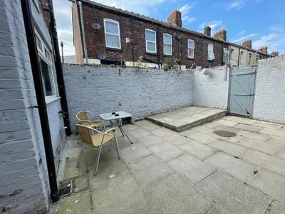 a patio with a table and chairs in front of a brick building at The LFC Red House - Spacious House With 5 Bedrooms, 2 Bathrooms, Street Parking And 1 Minute From The Stadium in Liverpool