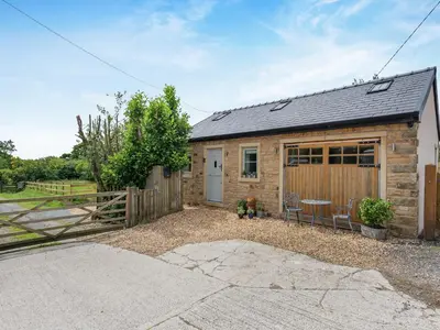 a small stone house with a gate and a fence at The Coop in West Bradford