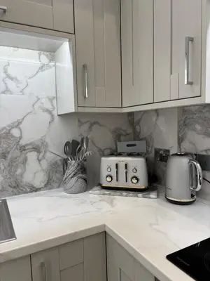 a kitchen with white cabinets and a counter top at Modern Top Floor Aparment Near Beach Luxury in Crosby