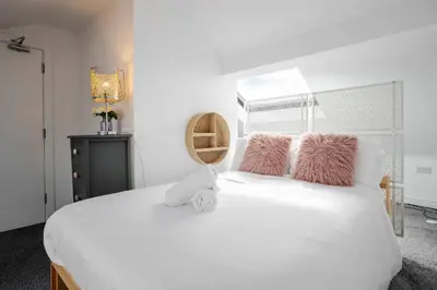 a bedroom with a white bed with pink pillows at Santiago 4 in Southport