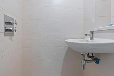 a white bathroom with a sink and a tiled wall at 2 Bed, 2 Bath New Build Apartment next to Albert Dock Liverpool & M&S Bank Arena - With Juliet Balcony - Monarchs Quay Arena Apartments - Close to Liverpool ONE Shopping, Exhibition Centre Liverpool, Pullman Hotel, Bars & Restaurants in Liverpool