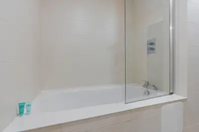 a white bathroom with a sink and a shower at 2 Bed, 2 Bath New Build Apartment next to Albert Dock Liverpool & M&S Bank Arena - With Juliet Balcony - Monarchs Quay Arena Apartments - Close to Liverpool ONE Shopping, Exhibition Centre Liverpool, Pullman Hotel, Bars & Restaurants in Liverpool
