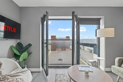 a living room with a table and a large window at 2 Bed, 2 Bath New Build Apartment next to Albert Dock Liverpool & M&S Bank Arena - With Juliet Balcony - Monarchs Quay Arena Apartments - Close to Liverpool ONE Shopping, Exhibition Centre Liverpool, Pullman Hotel, Bars & Restaurants in Liverpool