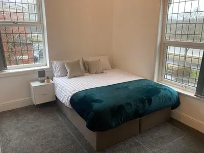 a bed in a bedroom with two windows at 6 bedroom house with Riverviews - Free parking in Preston