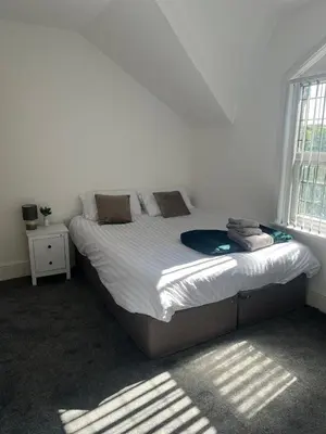 a bedroom with a bed with white sheets and a window at 6 bedroom house with Riverviews - Free parking in Preston