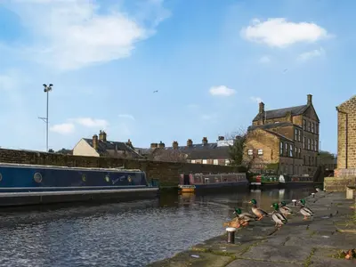 a group of ducks sitting on the side of a river at Madeline Cottage in Clitheroe