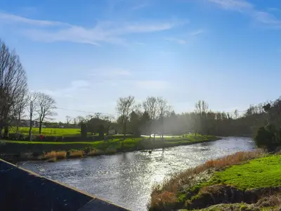 a river with a bridge in the foreground at Madeline Cottage in Clitheroe