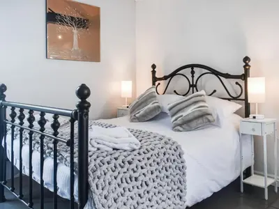 a bedroom with a black bed with white sheets and pillows at Madeline Cottage in Clitheroe